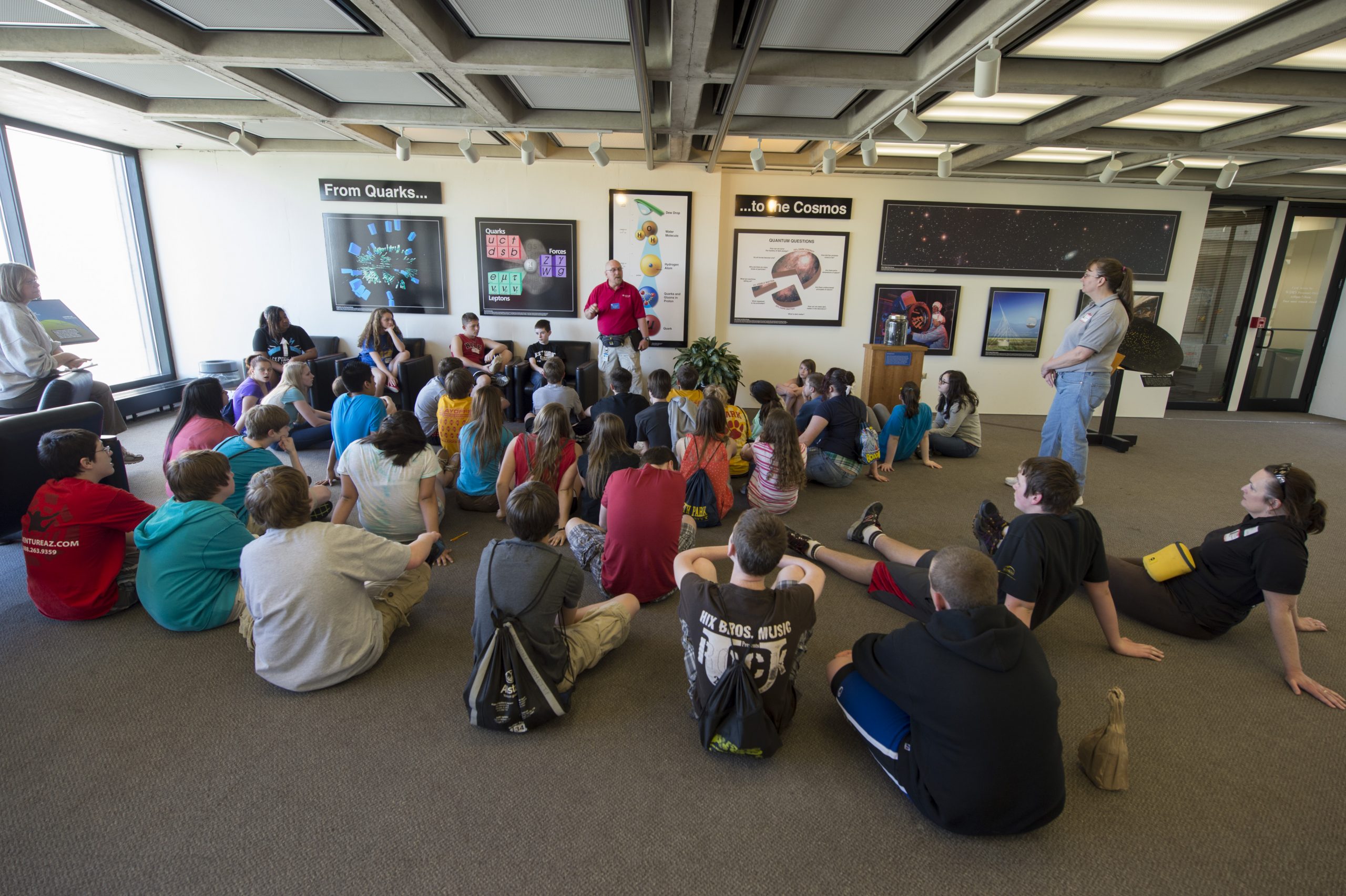 Students on a field trip sit on the floor.