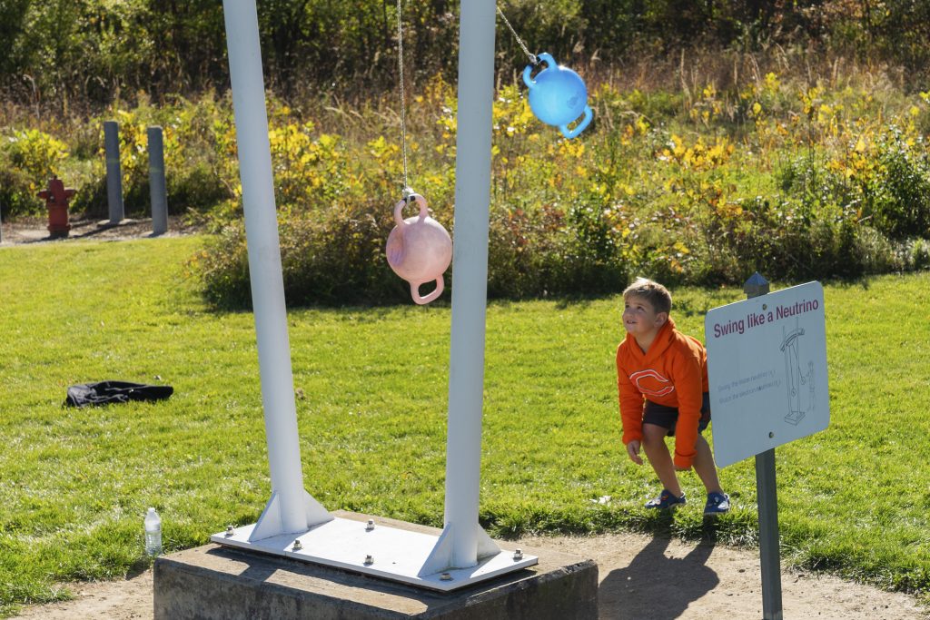 A small child watches the Swing like a Neutrino exhibit in the Outdoor Exhibits. 