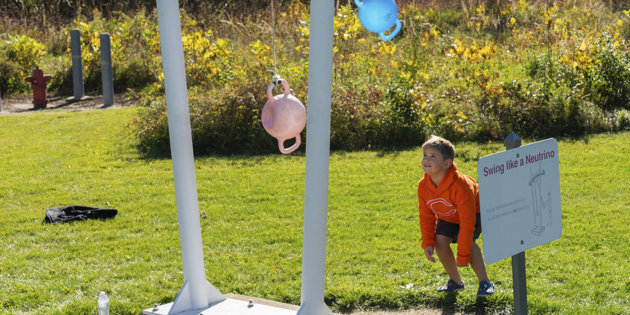 A small child watches the Swing like a Neutrino exhibit in the Outdoor Exhibits.